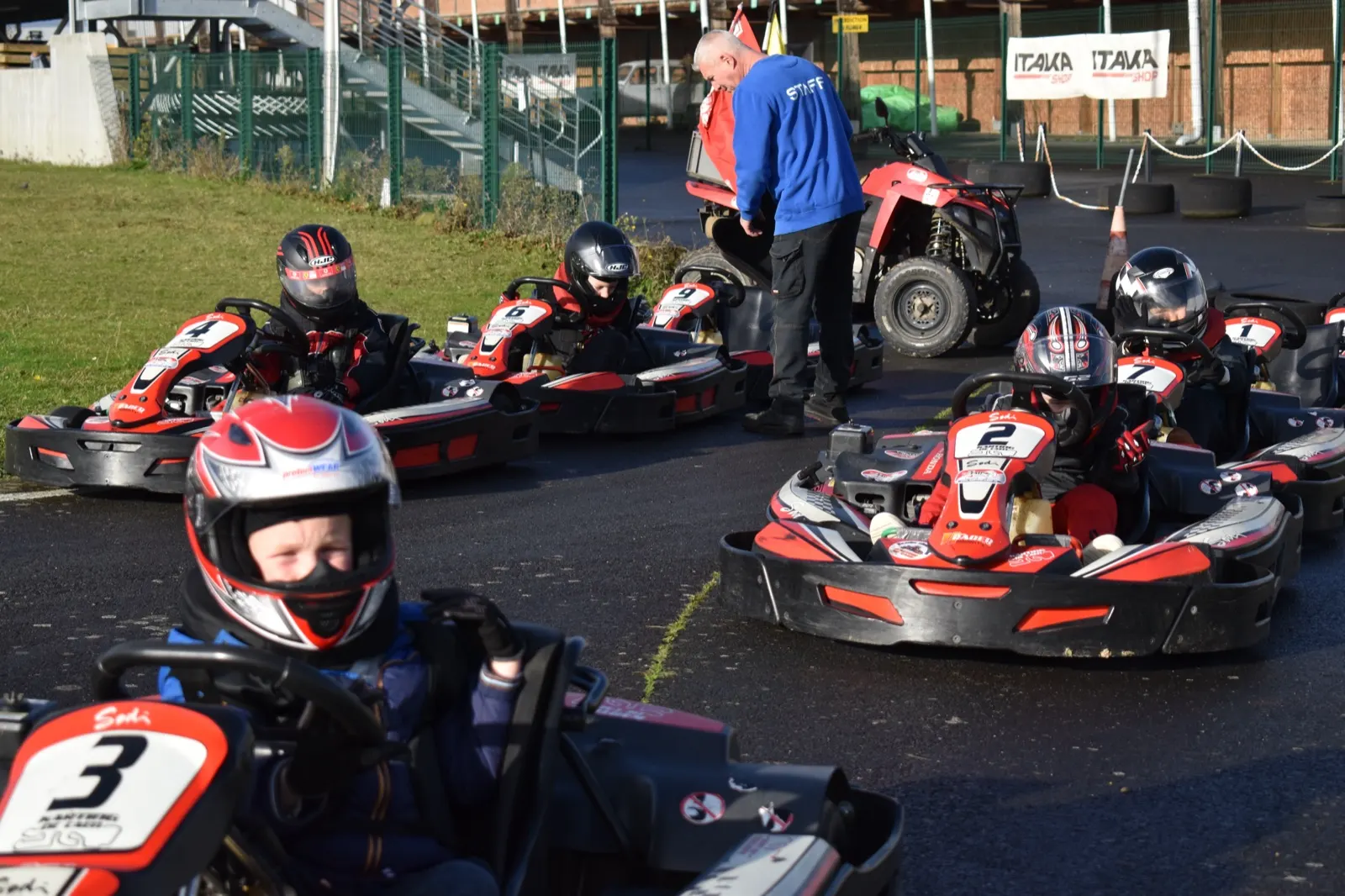 Jeunes pilotes casqués dans leurs karts avant le départ