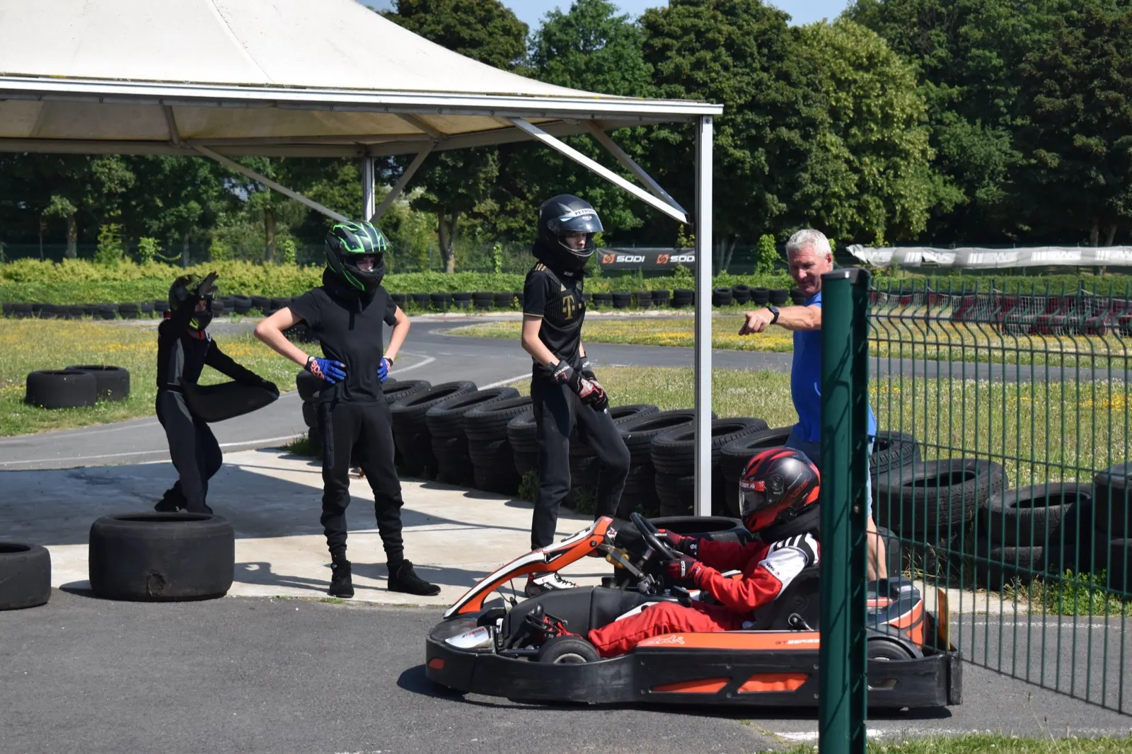 Groupe en combinaison autour d'un kart, sous le barnum